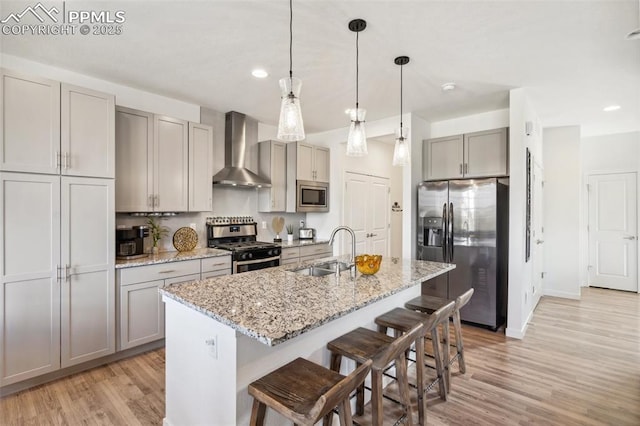 kitchen with a sink, light wood-style flooring, wall chimney exhaust hood, stainless steel appliances, and gray cabinetry
