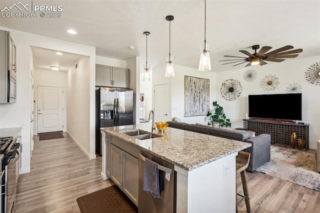 kitchen featuring stainless steel appliances, gray cabinetry, a sink, and light wood-type flooring