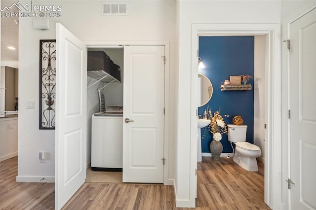 laundry room featuring laundry area, visible vents, washer / dryer, baseboards, and light wood finished floors