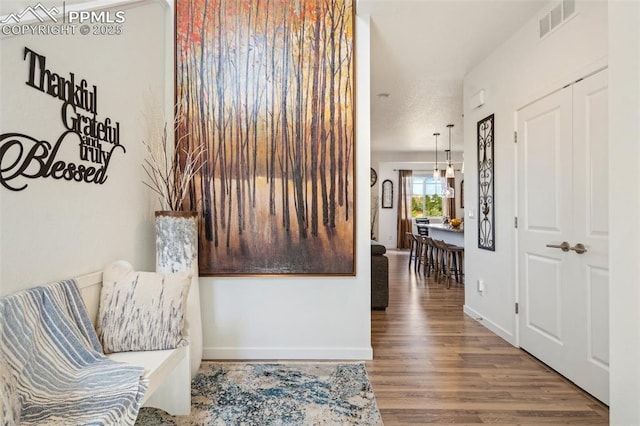 hall with baseboards, visible vents, and wood finished floors