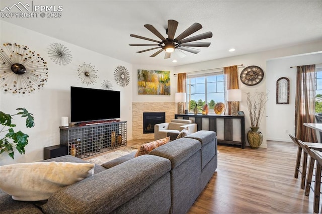living room featuring plenty of natural light, recessed lighting, a glass covered fireplace, and wood finished floors