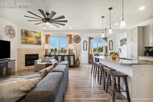 living room featuring wood finished floors, a fireplace, baseboards, recessed lighting, and a ceiling fan