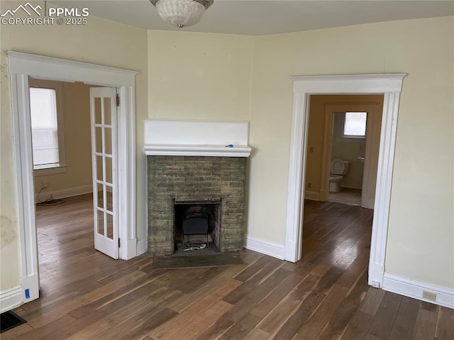 unfurnished living room featuring visible vents, a fireplace with flush hearth, baseboards, and dark wood finished floors
