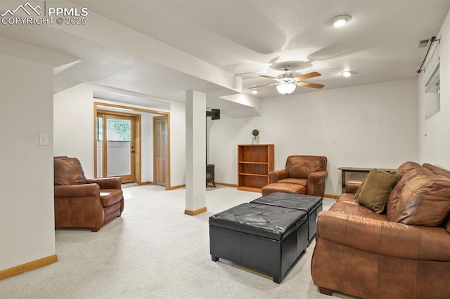 living area featuring a wood stove, baseboards, ceiling fan, and light colored carpet