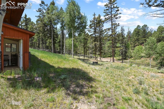 view of yard with a forest view and fence