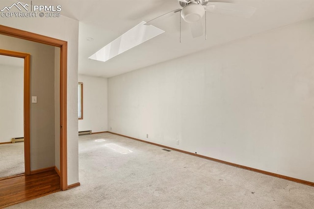 unfurnished room featuring a skylight, a baseboard radiator, baseboards, and carpet floors
