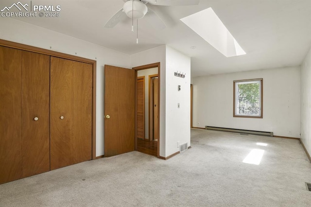 unfurnished bedroom with a baseboard heating unit, baseboards, visible vents, a skylight, and carpet
