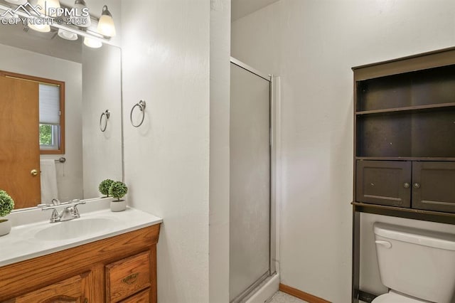 bathroom featuring toilet, a shower stall, and vanity