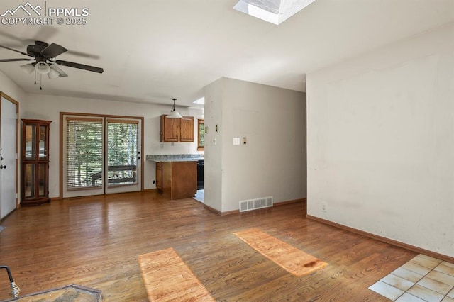 unfurnished living room featuring visible vents, light wood-style flooring, ceiling fan, and baseboards