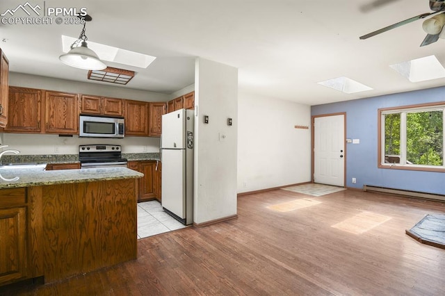 kitchen with light wood-style floors, a skylight, stainless steel appliances, a baseboard radiator, and brown cabinets