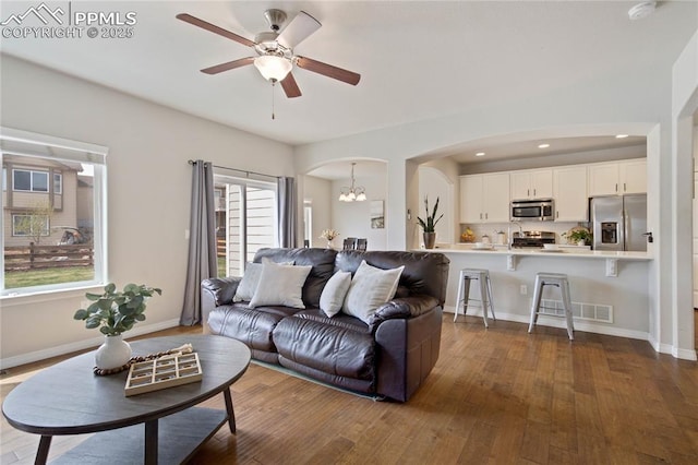 12529 Culebra Peak Dr, Peyton, CO 80831 - living room featuring arched walkways, baseboards, dark wood-style floors, and ceiling fan with notable chandelier