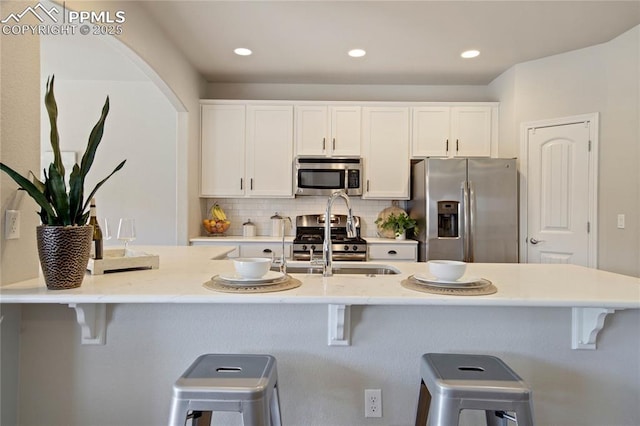 12529 Culebra Peak Dr, Peyton, CO 80831 - kitchen featuring a kitchen breakfast bar, stainless steel appliances, backsplash, white cabinetry, and recessed lighting