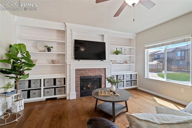 12529 Culebra Peak Dr, Peyton, CO 80831 - living area with baseboards, a ceiling fan, a brick fireplace, and wood finished floors
