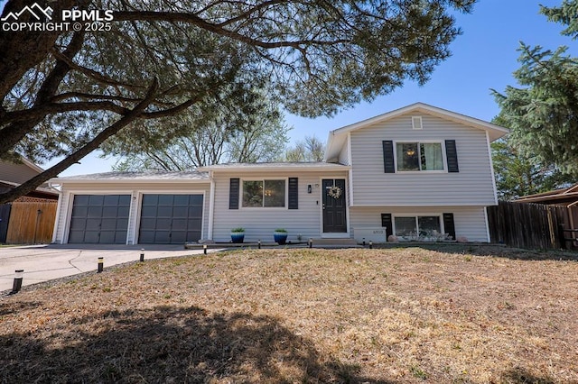 tri-level home featuring concrete driveway, an attached garage, and fence