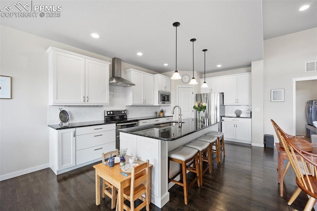 4225 New Santa Fe Trl, Colorado Springs, CO 80924 - kitchen featuring wall chimney range hood, appliances with stainless steel finishes, a sink, a kitchen bar, and decorative backsplash