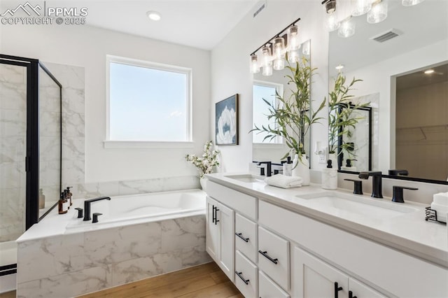 full bathroom featuring a shower stall, visible vents, a sink, and wood finished floors