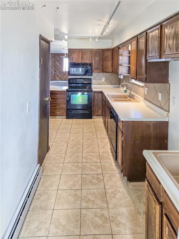 722 6th St, Hugo, CO 80821 - kitchen with black appliances, a baseboard radiator, a sink, track lighting, and tasteful backsplash