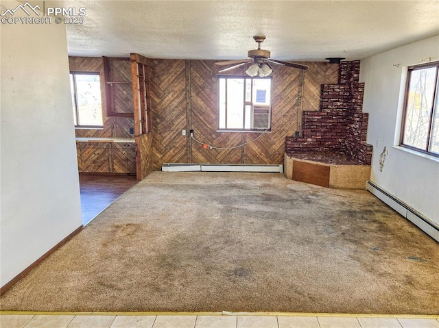 722 6th St, Hugo, CO 80821 - unfurnished living room with baseboard heating, wooden walls, healthy amount of natural light, carpet floors, and a textured ceiling