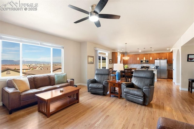 living area featuring ceiling fan, light wood finished floors, arched walkways, recessed lighting, and baseboards