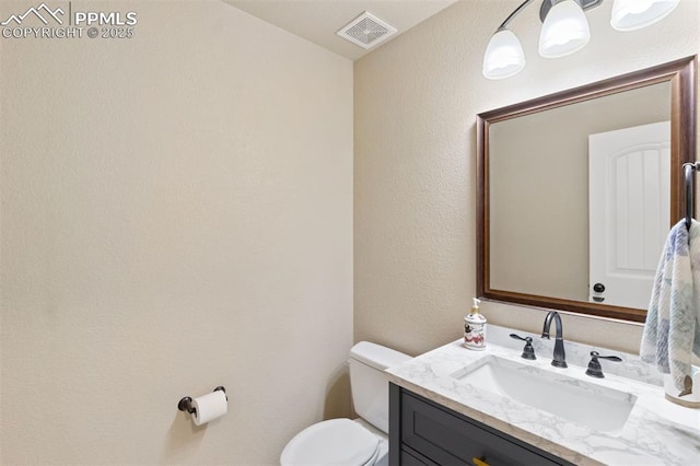 half bath with vanity, toilet, and visible vents