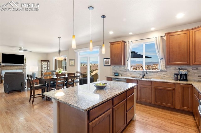 kitchen with a sink, backsplash, brown cabinets, and decorative light fixtures