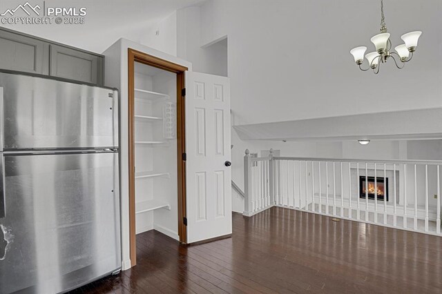 unfurnished dining area with a chandelier, dark wood finished floors, and vaulted ceiling