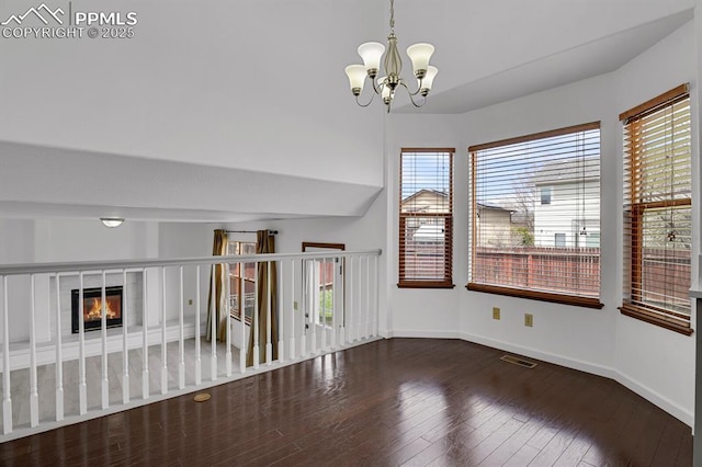 unfurnished dining area featuring a wealth of natural light, an inviting chandelier, hardwood / wood-style floors, and baseboards