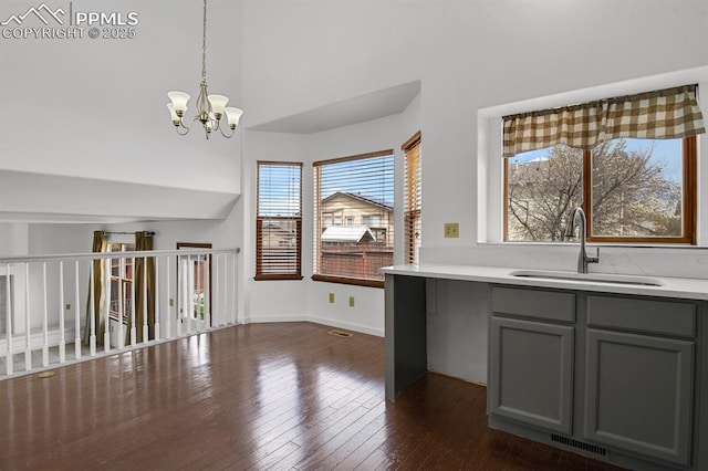 unfurnished dining area featuring an inviting chandelier, visible vents, a sink, and dark wood-type flooring