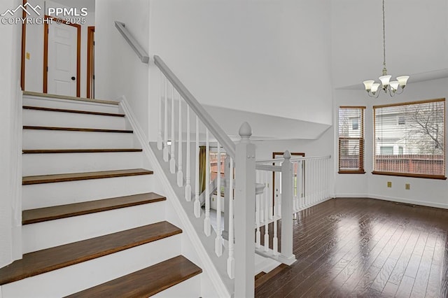 stairway with hardwood / wood-style flooring, an inviting chandelier, and baseboards