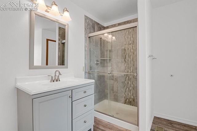 full bathroom featuring wood finished floors, vanity, a stall shower, and visible vents