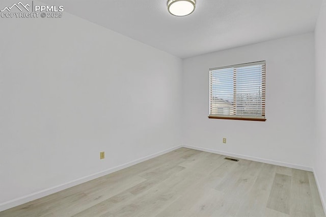 unfurnished room with light wood-type flooring, visible vents, and baseboards