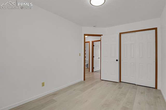 unfurnished bedroom featuring light wood-type flooring, baseboards, and a closet