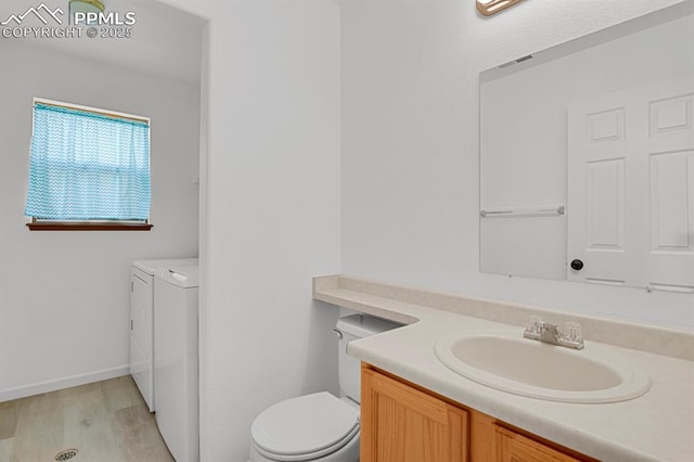 bathroom featuring toilet, baseboards, separate washer and dryer, wood finished floors, and vanity