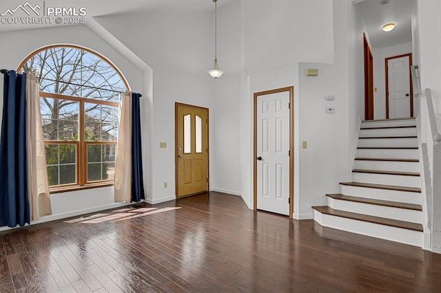 foyer entrance featuring baseboards, wood finished floors, a wealth of natural light, and stairway