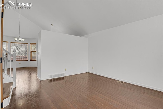 spare room with dark wood-style flooring, baseboards, visible vents, an inviting chandelier, and stairway
