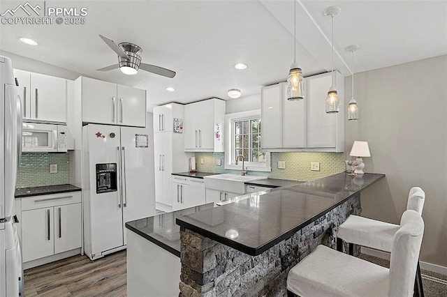 kitchen with tasteful backsplash, dark countertops, a ceiling fan, wood finished floors, and white appliances