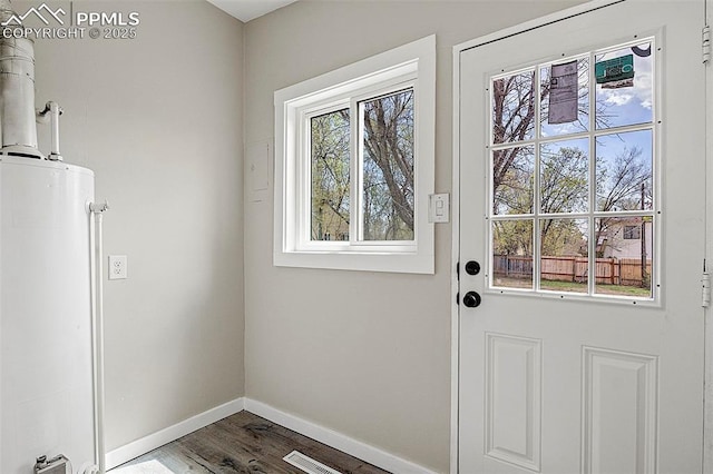doorway to outside with baseboards, visible vents, wood finished floors, and gas water heater