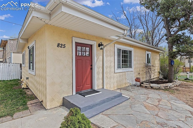 doorway to property with stucco siding, fence, and a patio area