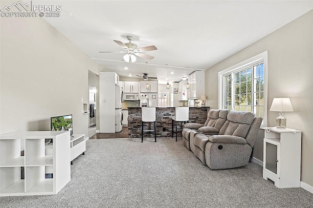 carpeted living room with a ceiling fan and baseboards