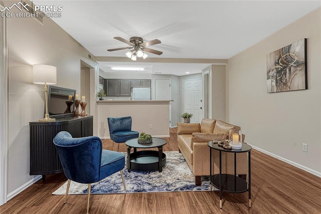 living area with baseboards, a ceiling fan, and wood finished floors