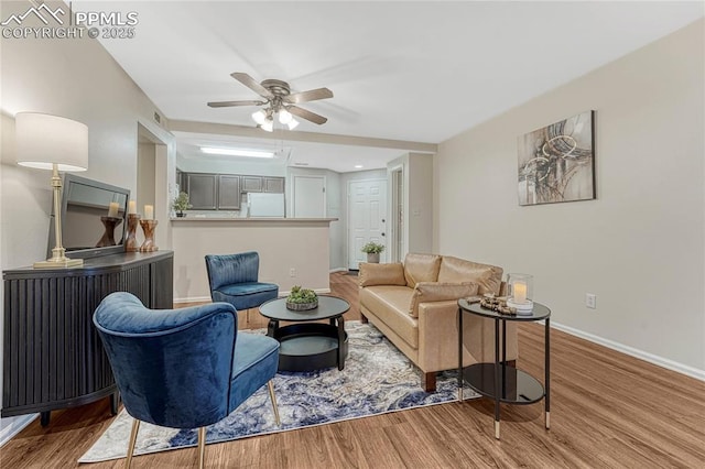 living area with baseboards, a ceiling fan, and wood finished floors