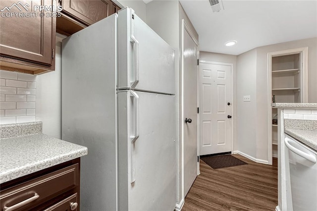 kitchen with decorative backsplash, dark brown cabinetry, dark wood finished floors, dishwasher, and freestanding refrigerator