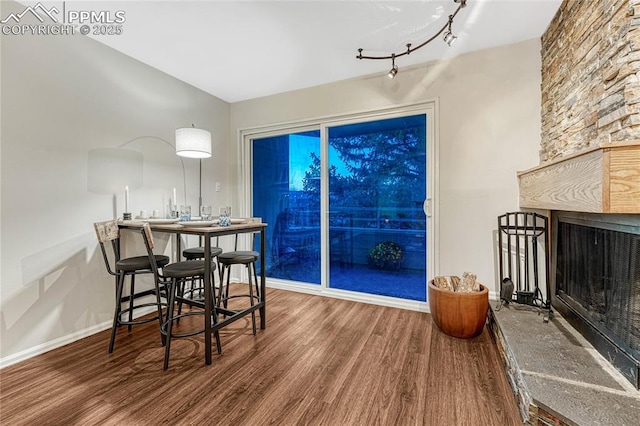 dining room with a large fireplace, baseboards, and wood finished floors