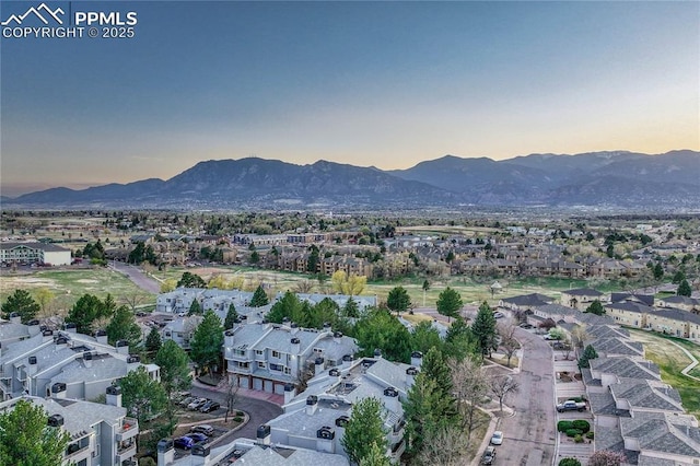 aerial view at dusk featuring a mountain view and a residential view