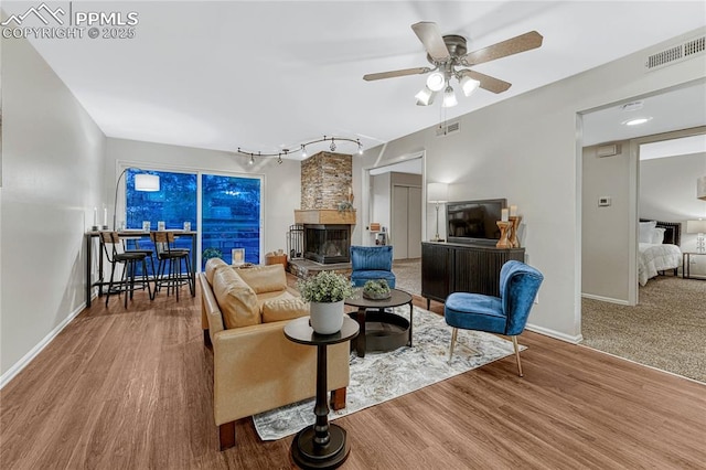 living room featuring baseboards, a ceiling fan, wood finished floors, and visible vents