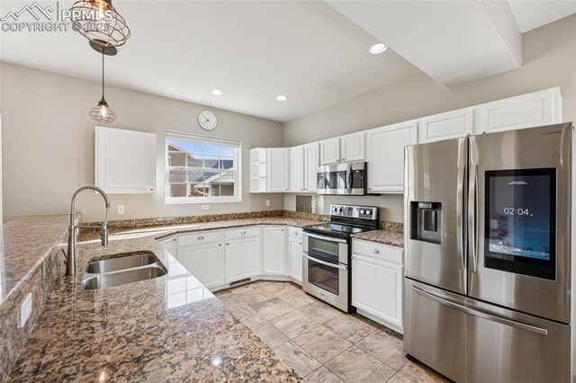kitchen featuring a sink, hanging light fixtures, white cabinets, appliances with stainless steel finishes, and light stone countertops
