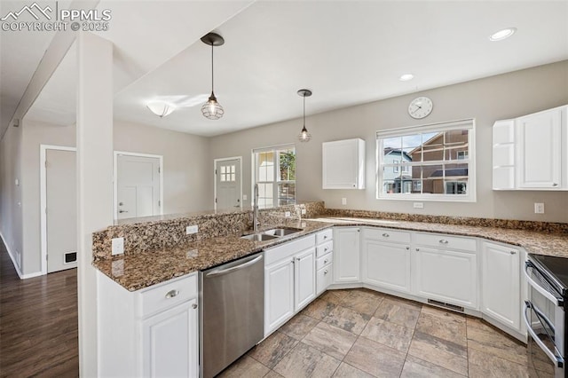kitchen featuring a sink, stainless steel appliances, decorative light fixtures, a peninsula, and white cabinetry
