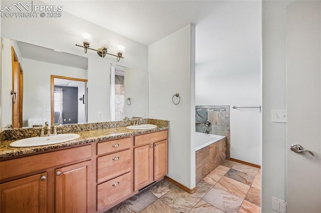 bathroom with tiled tub, baseboards, a sink, and double vanity