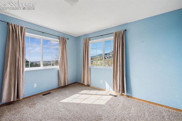 carpeted empty room featuring baseboards and visible vents