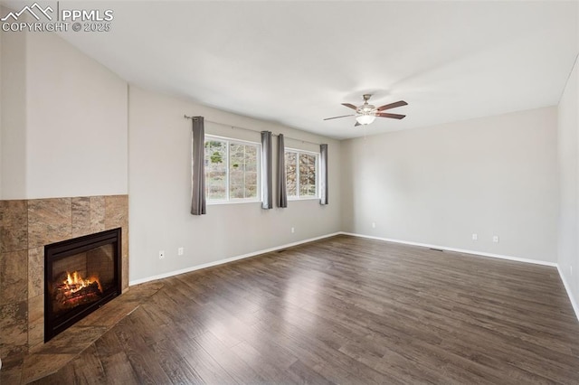 unfurnished living room with a ceiling fan, baseboards, a fireplace, and dark wood finished floors